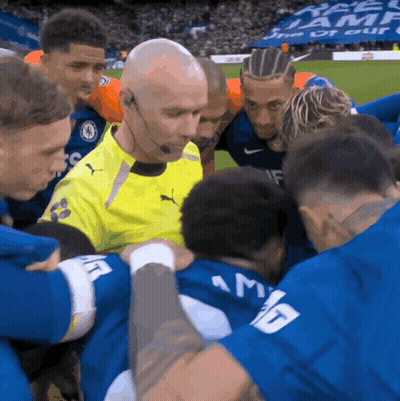 Soccer Players Huddle Around Referee In Yellow Puma Jersey GIF