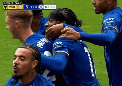 Soccer Players Hugging On Field With Premier League Scoreboard GIF