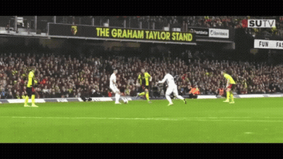 Soccer Players On A Field With A Sign That Says The Graham Taylor Stand In The Background GIF