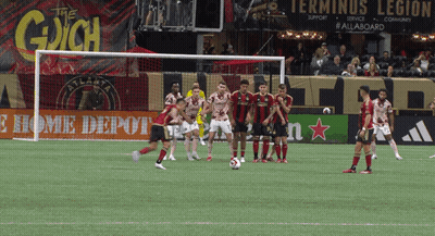 Soccer Players On Field In Front Of The Gaich Sign GIF