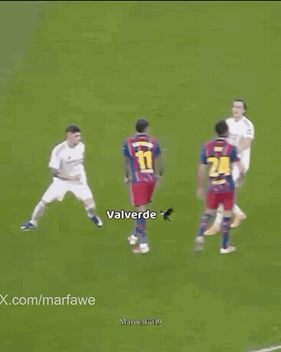 Soccer Players Standing Around Player Lying On Field GIF