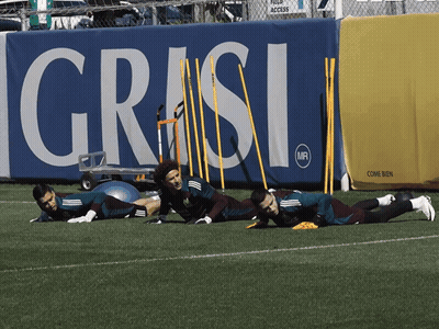 Soccer Players Stretching On Field In Front Of Grasi Sign GIF