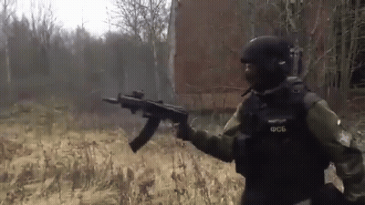Soldier Holding Gun In Field In Front Of Building GIF