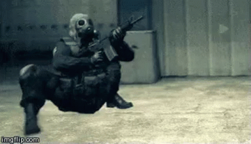 Soldier Wearing Gas Mask Holding Gun Sitting On Ground GIF