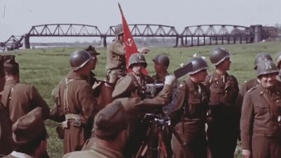 Soldiers Gathered in Field With Red Flag