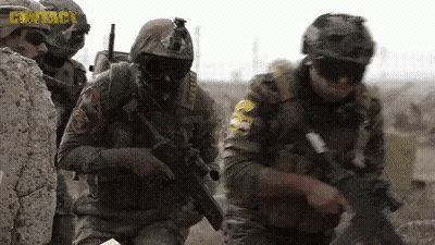 Soldiers In Helmets And Goggles Holding Guns In Field GIF