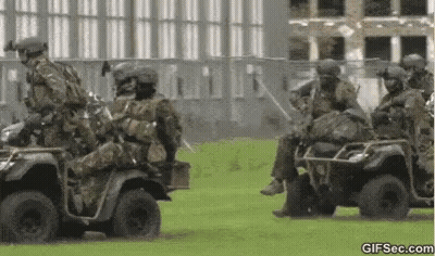 Soldiers Riding ATVs On Grassy Field GIF