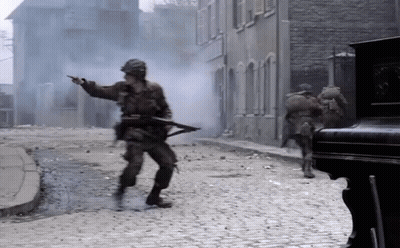 Soldiers Walking And Pointing On Cobblestone Street GIF