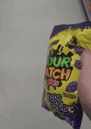 Someone Is Holding A Bag Of Sour Patch Kids Grape Raisin GIF