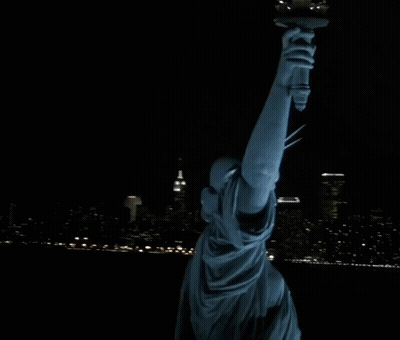 Statue Of Liberty Lit Up At Night With City Skyline GIF