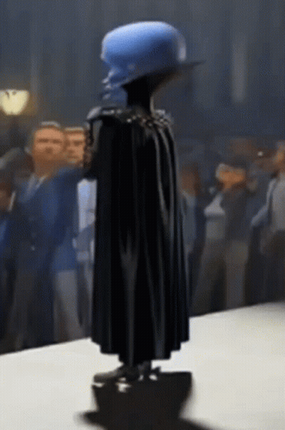 Statue Of Man In Cape And Blue Hat GIF