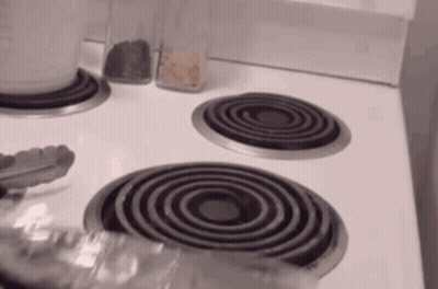 Stove Top With Three Burners And Tongs GIF