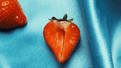 Fresa cortada por la mitad sobre superficie azul GIF