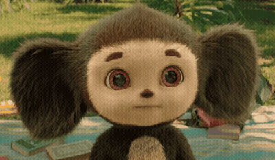 Stuffed Animal With Big Eyes Sitting On Blanket In Grass GIF