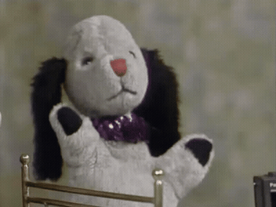 Stuffed Animal With Purple Bow Tie Sitting In Chair GIF