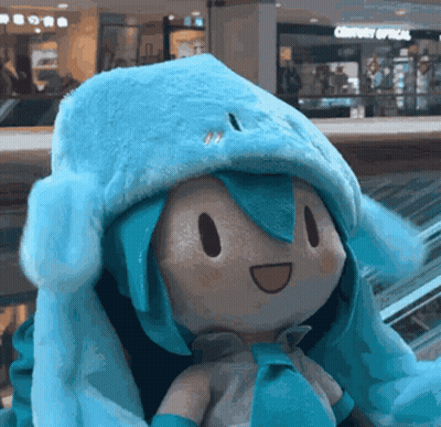 Stuffed Doll In Blue Hat Sitting On Escalator GIF