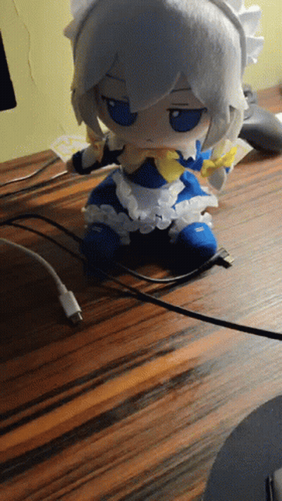 Stuffed Doll In Maid Outfit Sitting On Wooden Table GIF