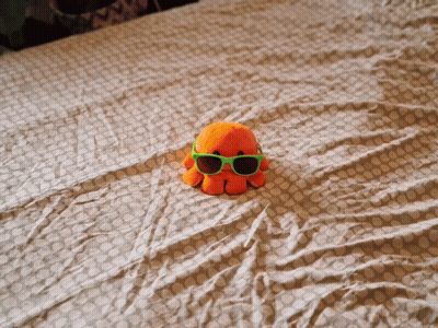 Stuffed Octopus Wearing Green Sunglasses On Bed GIF