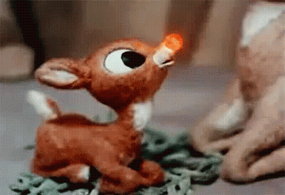 Stuffed Reindeer With Red Nose Sitting On Table GIF