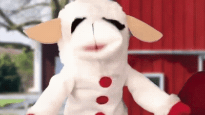 Stuffed Sheep Standing In Front Of Red Barn GIF