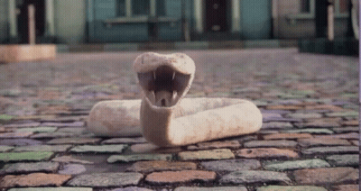 Stuffed Snake Laying On Cobblestone Street With Mouth Open GIF