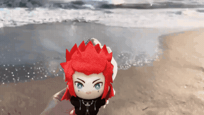 Stuffed Toy With Red Hair And Green Eyes On Beach GIF