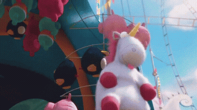 Stuffed Unicorn Sitting In Front Of Roller Coaster GIF
