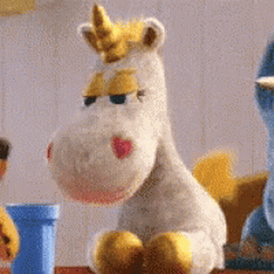 Stuffed Unicorn With Yellow Horn Sitting Beside Another Stuffed Animal GIF