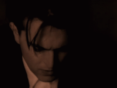 Suit-And-Tie Man Looking At Camera In Dark Room GIF