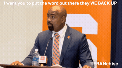 Suited Man At Podium With Water Bottle GIF