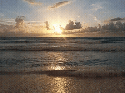 Sun Setting Over Ocean Waves On Beach GIF