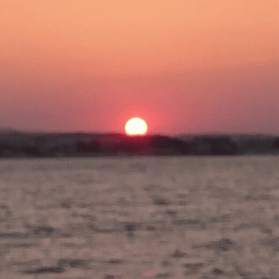 Sun Setting Over Ocean With Boat GIF