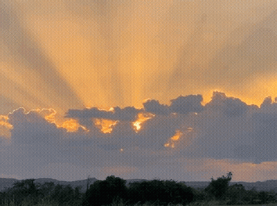Sun Shining Through Clouds At Sunset Over Field GIF