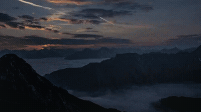 Sunset Over Mountain Range With Plane Flying GIF