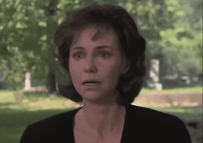 Surprised Woman Standing In Front Of Cemetery GIF