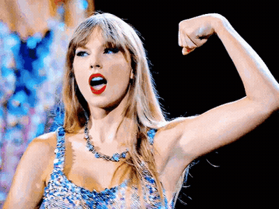 Taylor Swift Flexing Muscles In Blue Dress And Necklace GIF