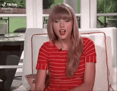 Taylor Swift In Red Striped Shirt Sitting With Mouth Open GIF