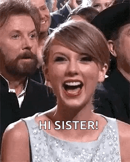 Taylor Swift Is Laughing In Front Of A Crowd Of People While A Man Looks On . GIF