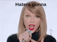 Taylor Swift Is Singing Into A Microphone With The Words `` Haters Gonna '' Written Above Her . GIF