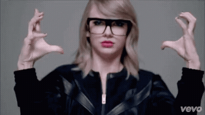 Taylor Swift Sitting On Couch In Black And White Sweater GIF