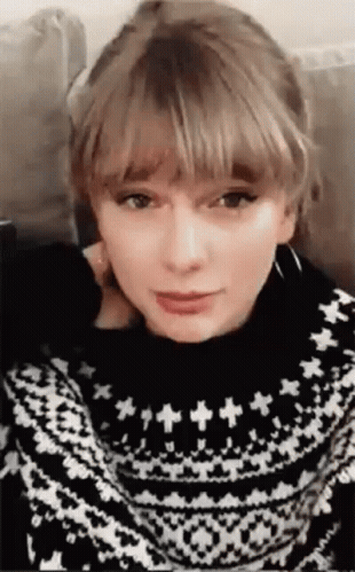 Taylor Swift Sitting On Couch In Black And White Sweater GIF