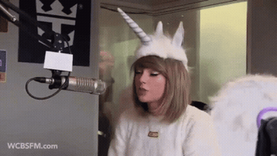 Taylor Swift Unicorn Hat And Wings Talking Into Microphone GIF