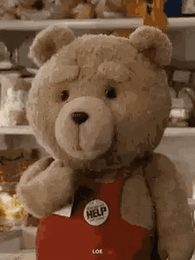 Teddy Bear In Red Apron With Help Button Next To Refrigerator GIF