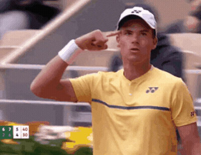 Tennis Player In Yellow Shirt And White Hat Pointing At Head GIF