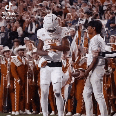 Texas Football Player Holding Ball In Front Of Crowd GIF