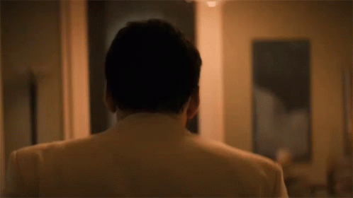 The Back Of A Man 'S Head Is Shown In A Room With A Painting In The Background . GIF