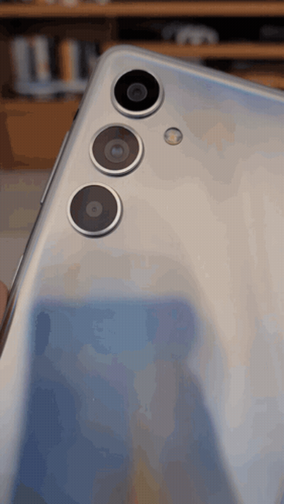 The Back Of A Silver Phone With Three Cameras GIF