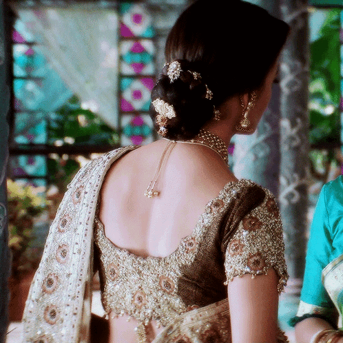 The Back Of A Woman 'S Blouse Has A Necklace Around Her Neck GIF