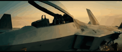 The Cockpit Of A Fighter Jet With The Canopy Open And A Sunset In The Background GIF
