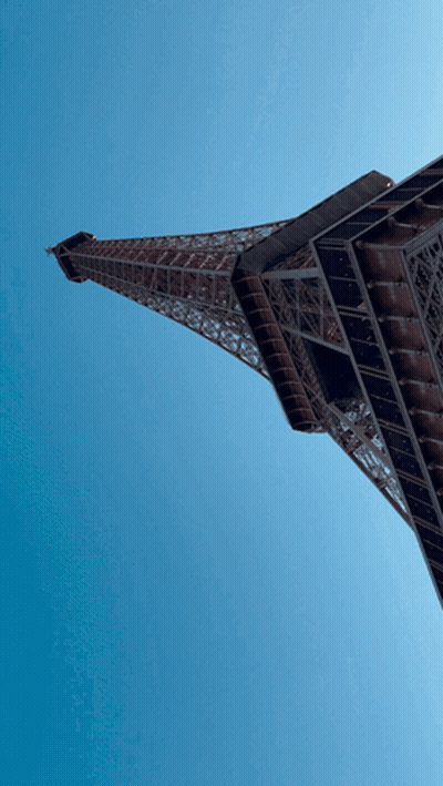 The Eiffel Tower Is Against A Blue Sky GIF